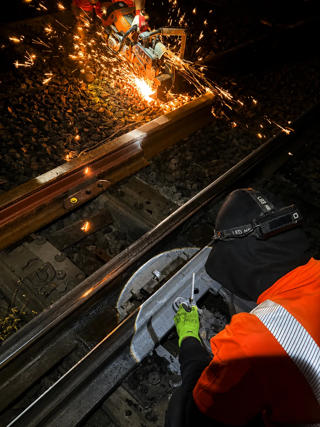 Trennen einer Schiene mit dem Trennschleifer – Funkenflug bei Nacht